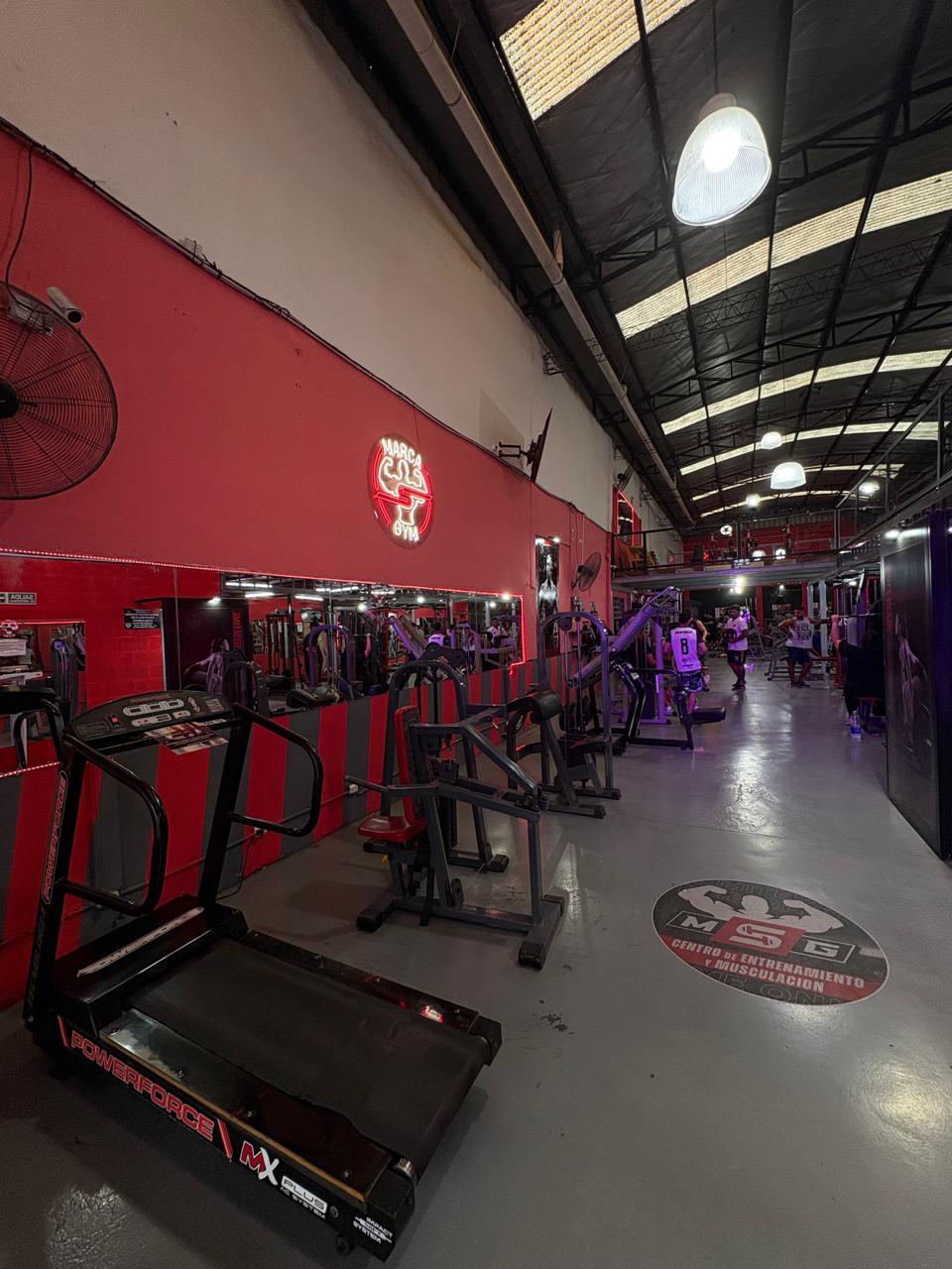 Sector de máquinas con el cartel de neón de Marca S Gym