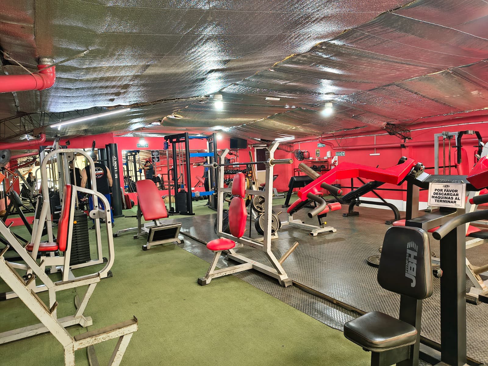 Máquinas de musculación con tapizado rojo y piso de goma